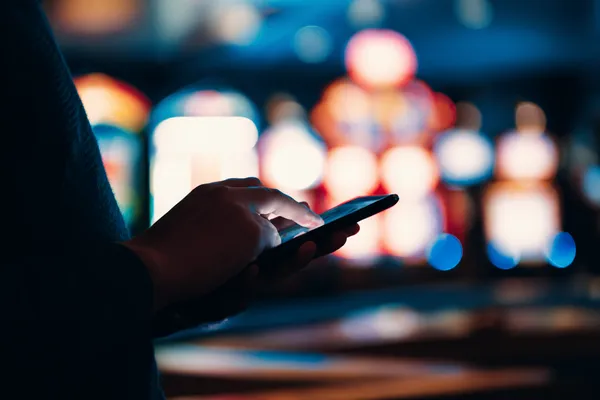 22BED Slots — Thousands of exciting themes and jackpots A stylish woman beside vibrant slot machines displaying glowing sevens, showcasing the variety of top slots at 22BED.