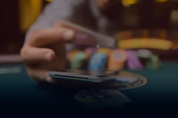 A person using their device against a moody casino-themed background, illustrating the smooth re-entry process at 22BED.